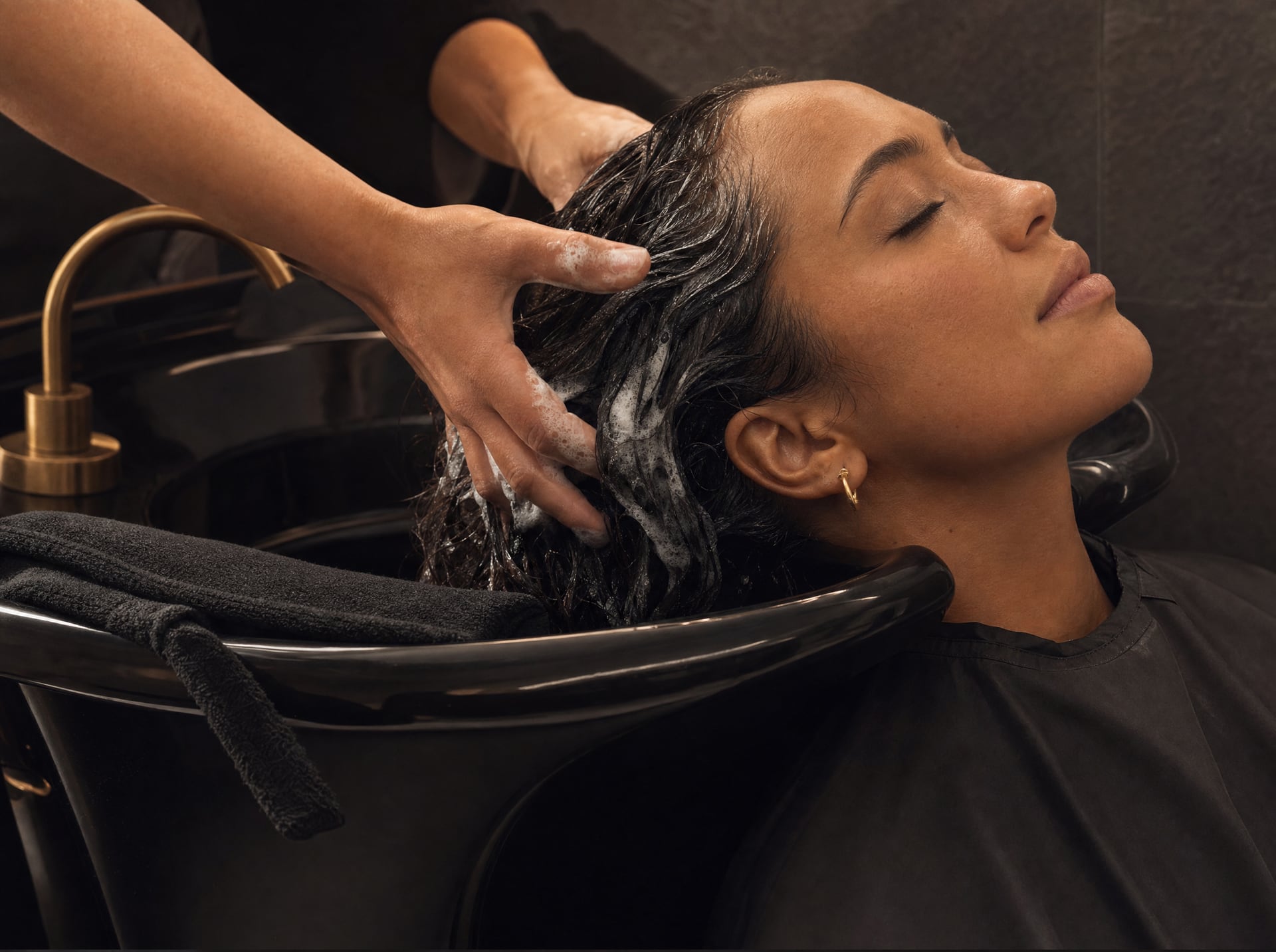 Rituel de shampooing au bac noir, avec massage du cuir chevelu.